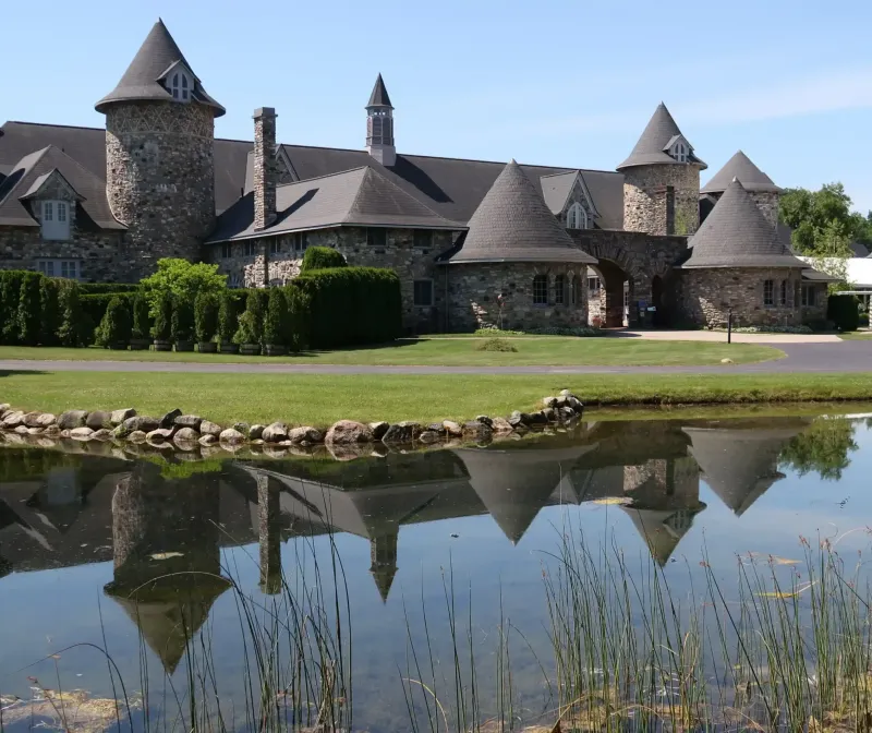A clear lake next to a green lawn and castle at Castle Farms.