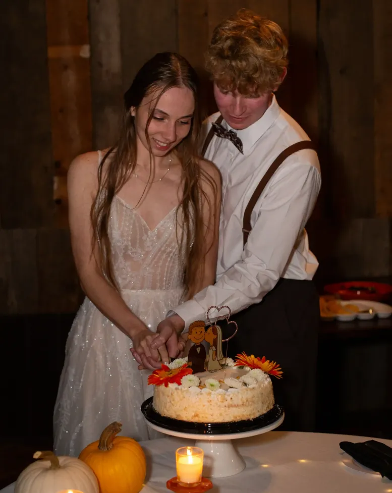 A bride and groom cutting a small cake at a table in the tavern at Castle Farms.