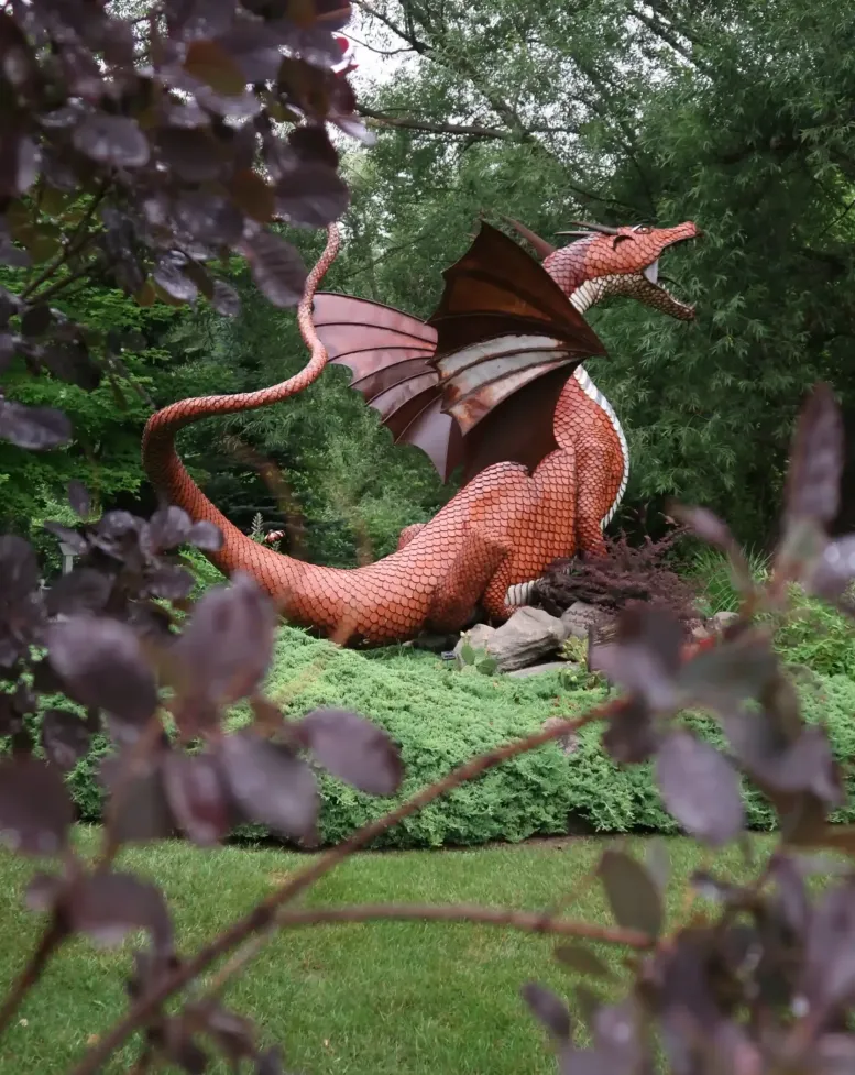 A red dragon statue overlooking the green lawn of Castle Farms.