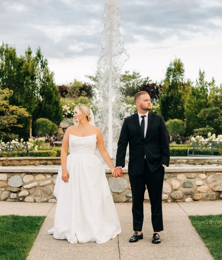 Bride and groom holding hands in front of the Castle Farms garden fountain. Photo credit: Kristina Sobel Photography.