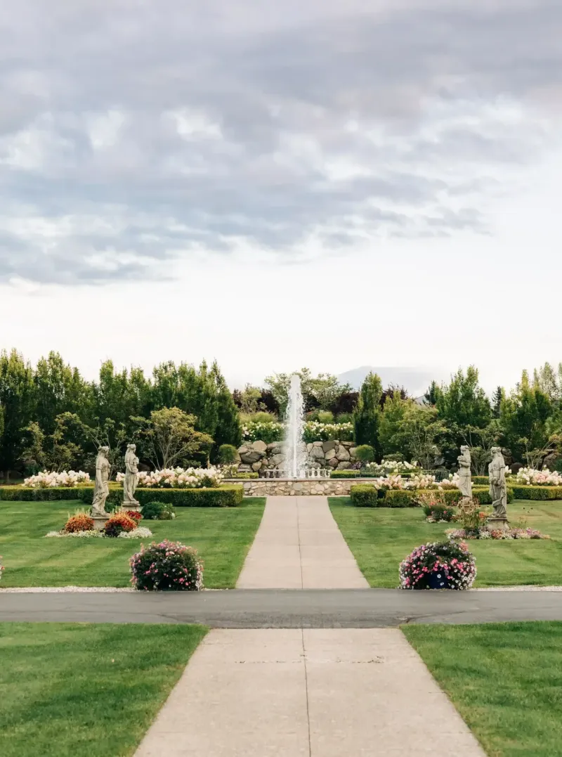 A sidewalk leading to a fountain in the gardens of the grounds of Castle Farms.
