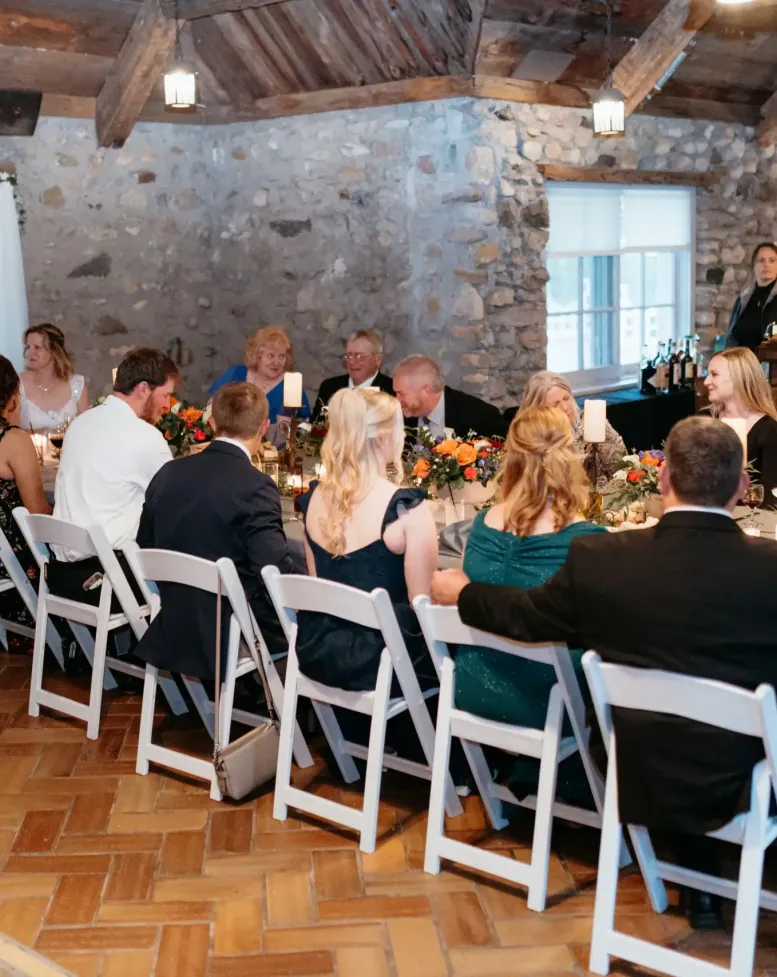 Wedding guests sit at a table eating dinner in the tavern at Castle Farms.
