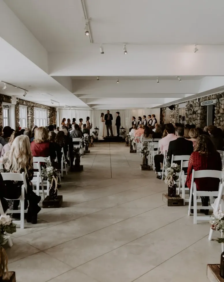 A wedding in a small event space with rows of chairs with guests at Castle Farms. 