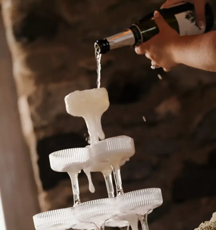 A champagne bottle pouring wine over a tower of drink glasses at a wedding at Castle Farms.