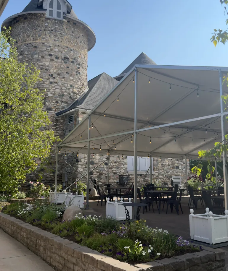 A side view of the Rose tent next to a stone tower at Castle Farms.