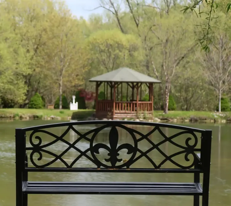 A metal bench with the Castle Farms logo beside a pond at Castle Farms.