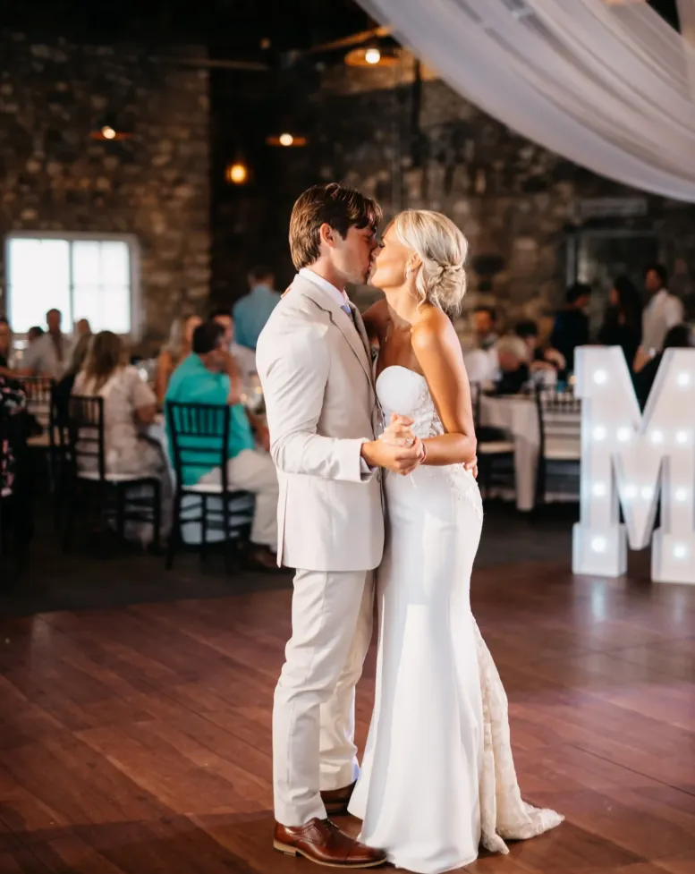 A bride and groom dance on a wooden dance floor in an event space decorated with draping white sheets at Castle Farms. 
