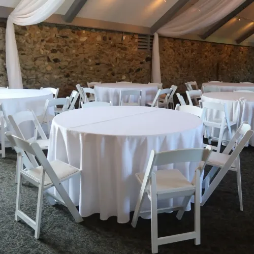 Tables with white linens and chairs in an event space at Castle Farms.
