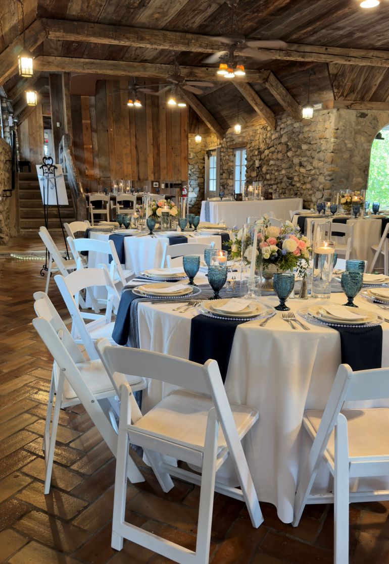 A dark tavern with white tables and chairs at Castle Farms.