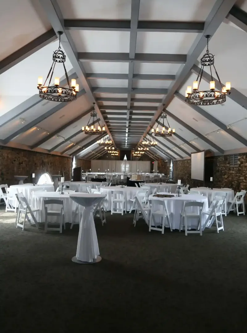 An event space with chandeliers hanging from the ceiling and tables scattered around the floor at Castle Farms.