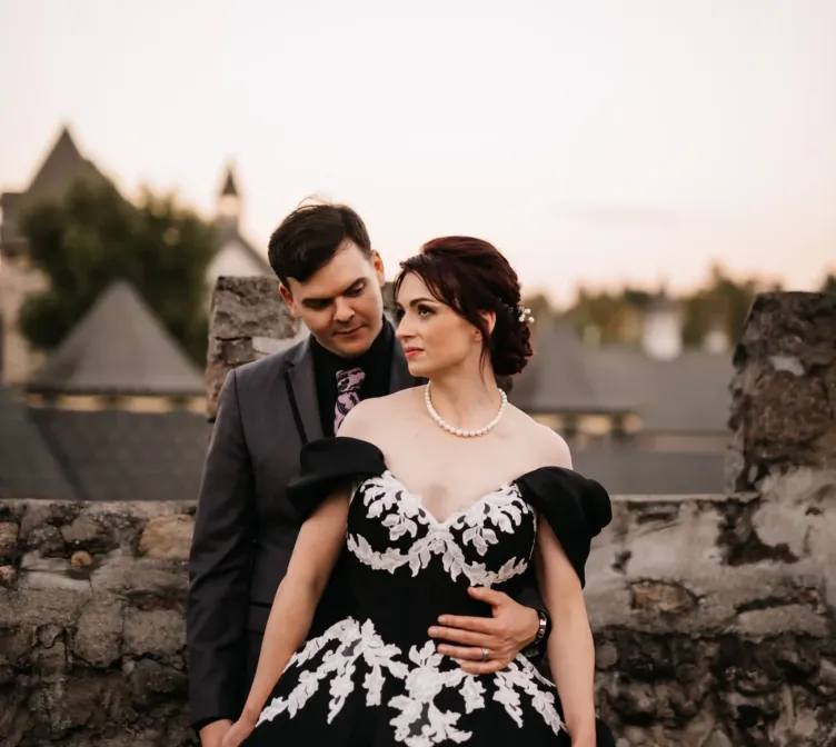 A bride and groom standing next to a stone wall on the grounds of Castle Farms.