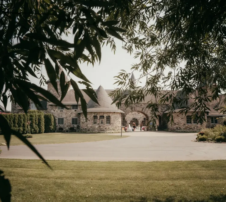 A view of buildings and a lawn from a grove of trees on the grounds of Castle Farms.