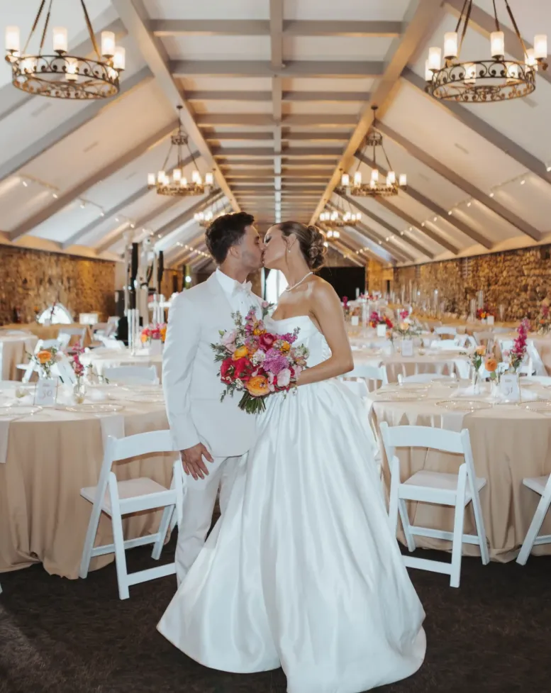 A bride and groom embracing in a decorated event space at Castle Farms. 