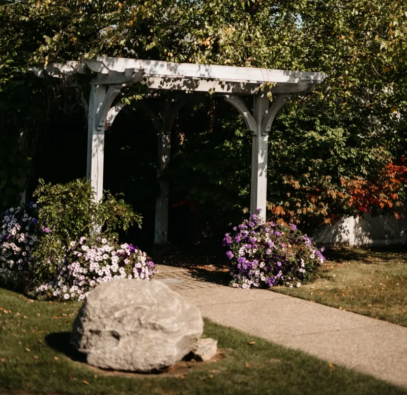 A white wooden arch with flowers in a garden at Castle Farms.
