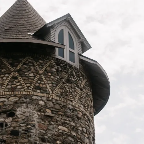 A stone tower with a window on a cloudy day at Castle Farms.