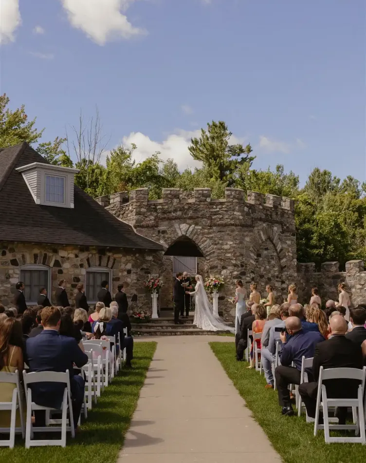 A wedding in a courtyard with guests sitting under a blue sky at Castle Farms.