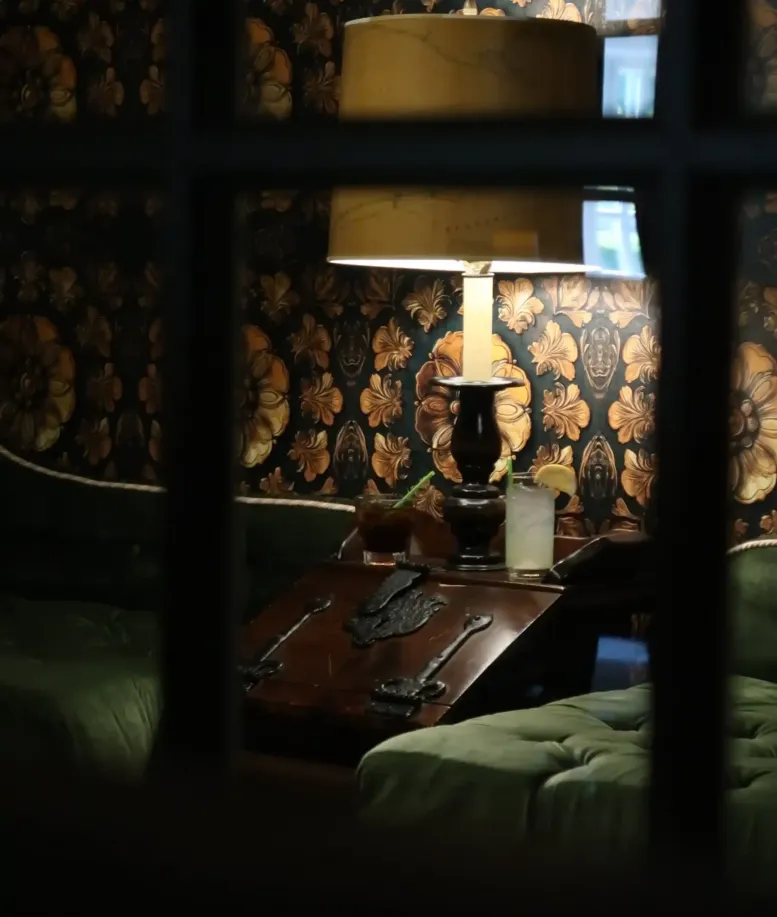 Charlevoix Bar  - A lamp lighting a dark corner with green couches in the Castle Pub at Castle Farms. 