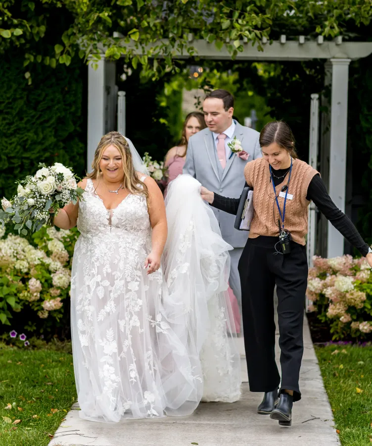 A bride walks in the gardens with a wedding planner at Castle Farms.