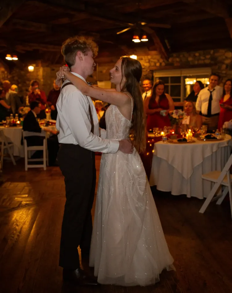A bride and groom dancing in the warm golden light of the tavern in Castle Farms.