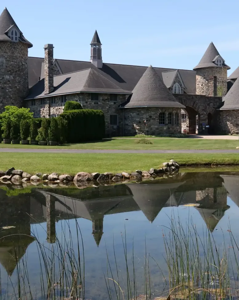 A clear lake next to a green lawn and castle at Castle Farms.