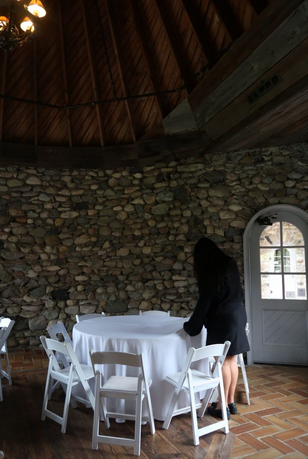 A woman adjusts a tablecloth on a long table at Castle Farms.
