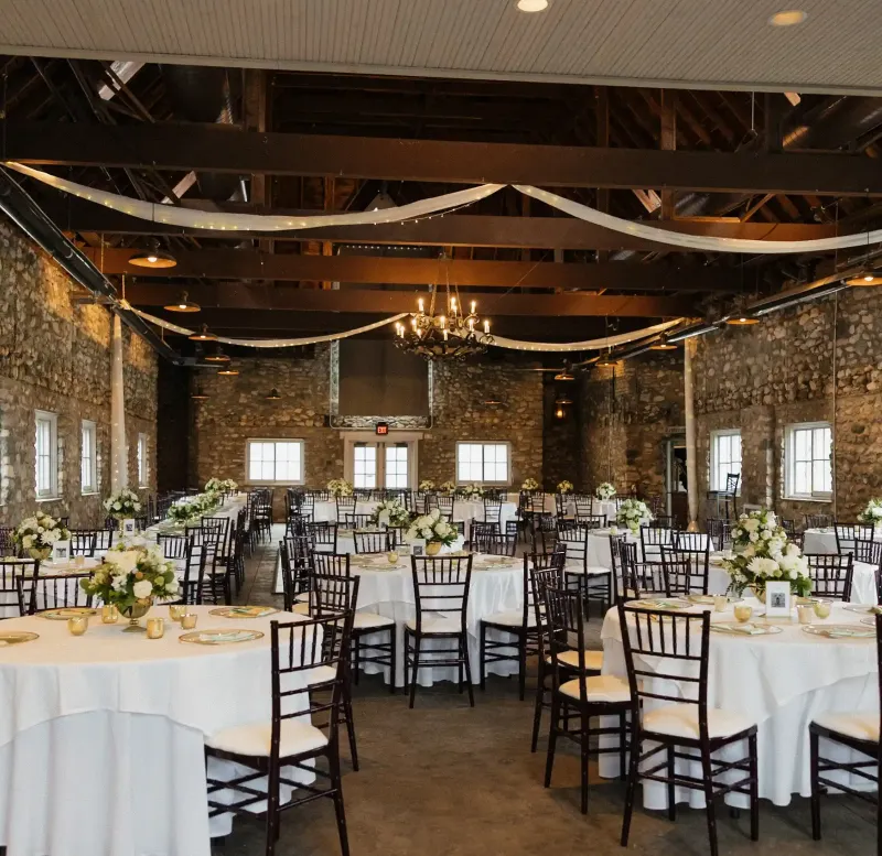 An event space decorated with white drapes and tables and chairs at Castle Farms.