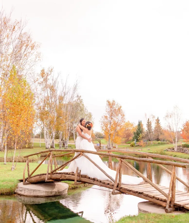 Wedding couple embracing on a wooden bridge surrounded by fall foliage at Castle Farms. Photo credit: Aubrey Elizabeth Photography.