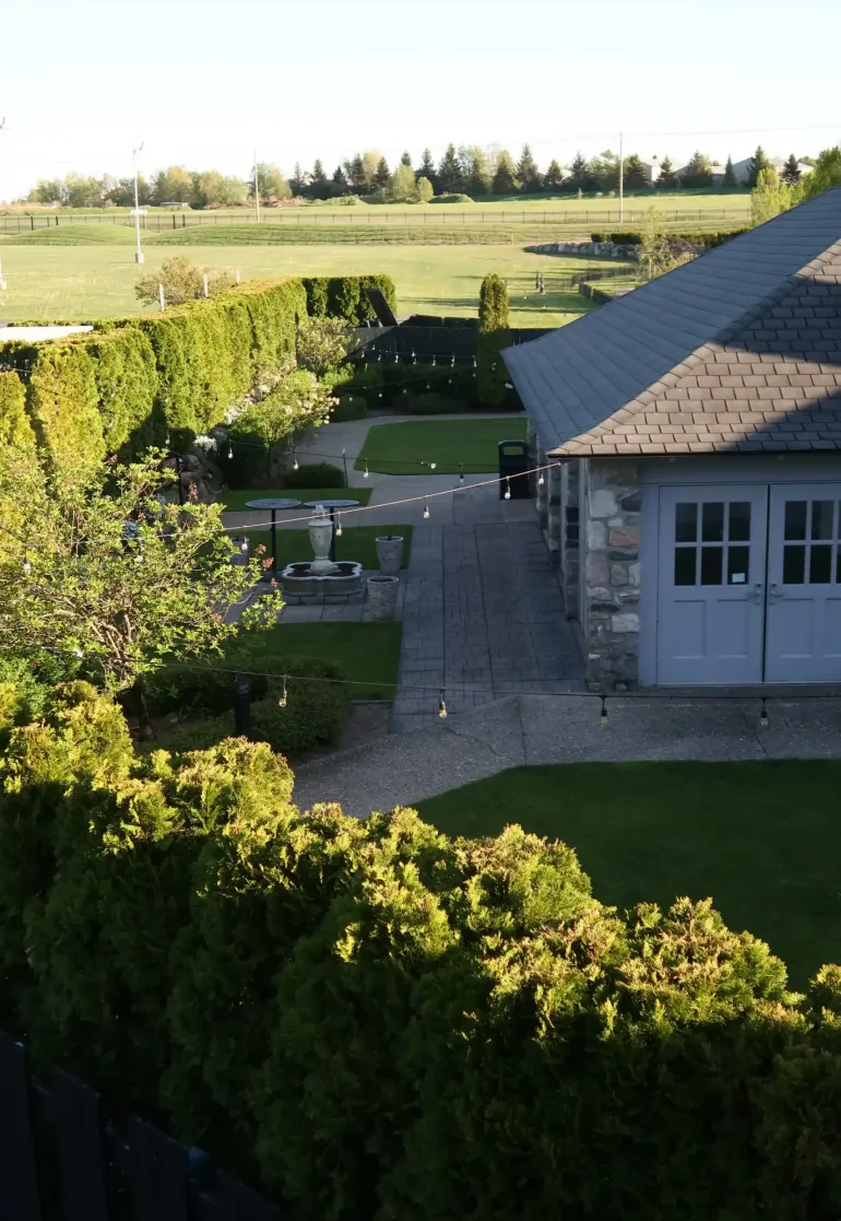 A yard with pavement, hedges, and string lights next to a building at Castle Farms.