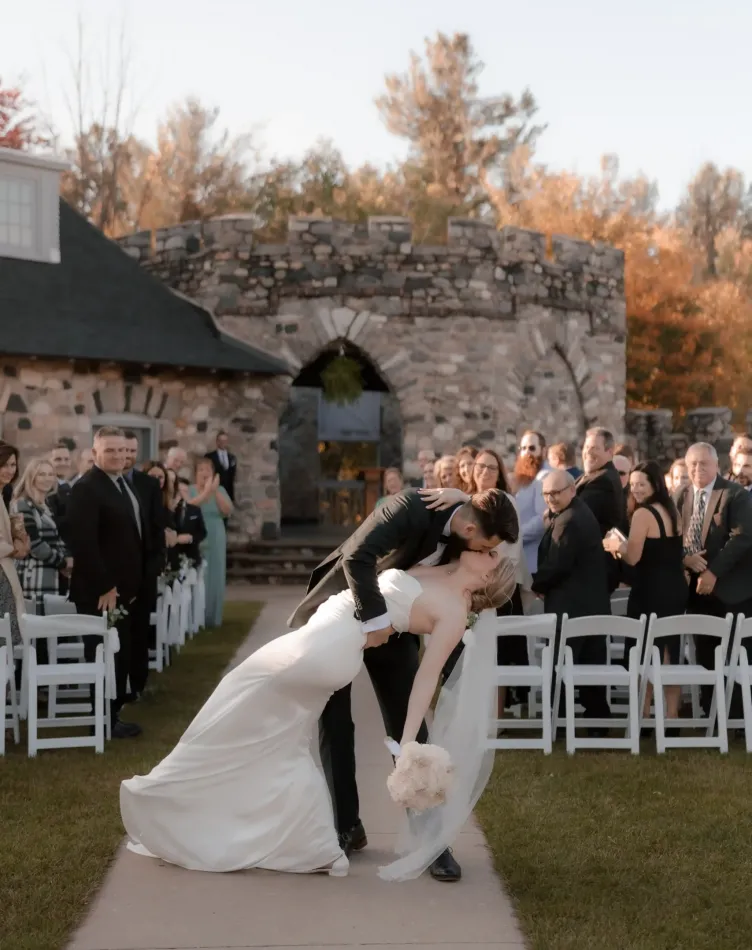 A groom dips his bride in front of the audience after a wedding in a courtyard at Castle Farms.