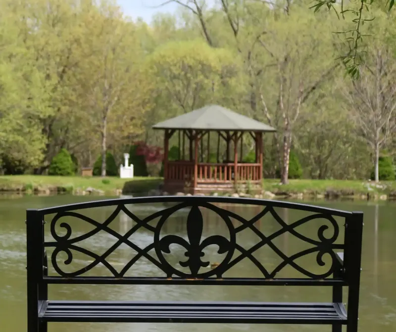 A metal bench with the Castle Farms logo beside a pond at Castle Farms.