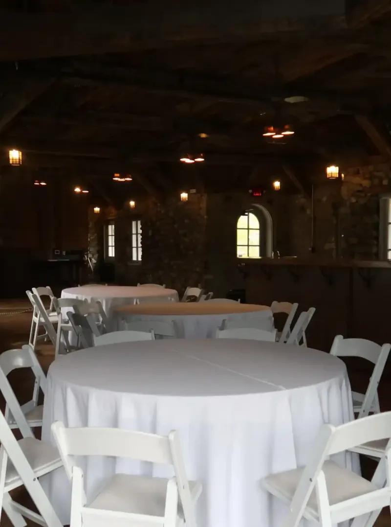 White tables and chairs in a stone-walled tavern at Castle Farms.