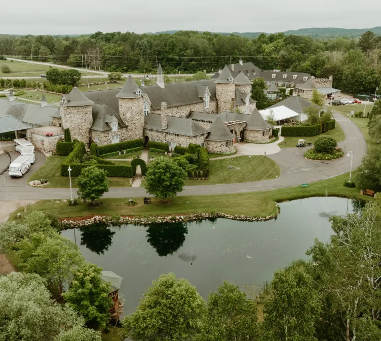 Overhead view of a pond and the venue surrounded by green trees at Castle Farms.