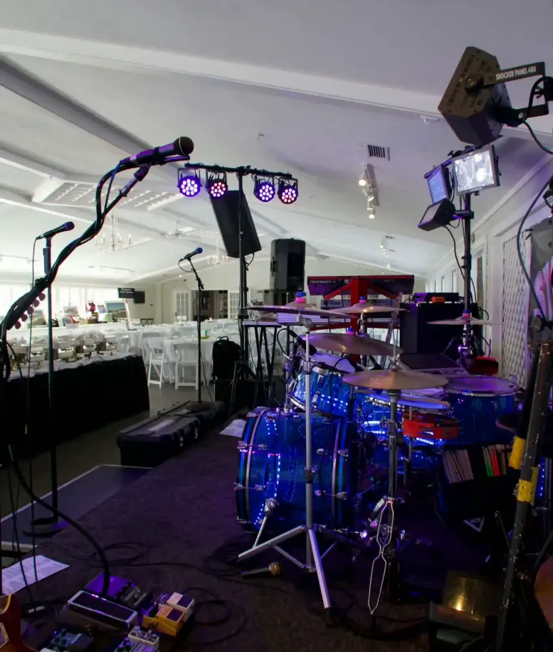 A drum set surrounded by light and sound equipment sitting on a stage in an event space at Castle Farms.