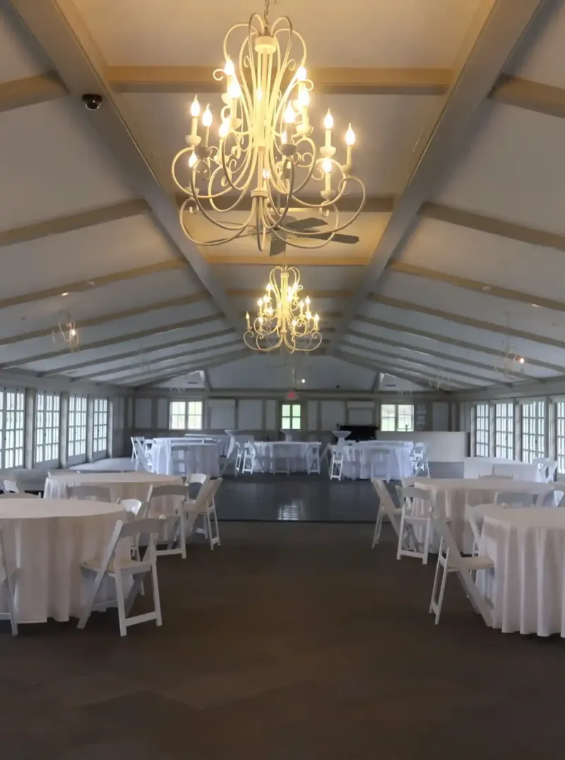 Event space with tables and chandeliers and a dance floor at Castle Farms.