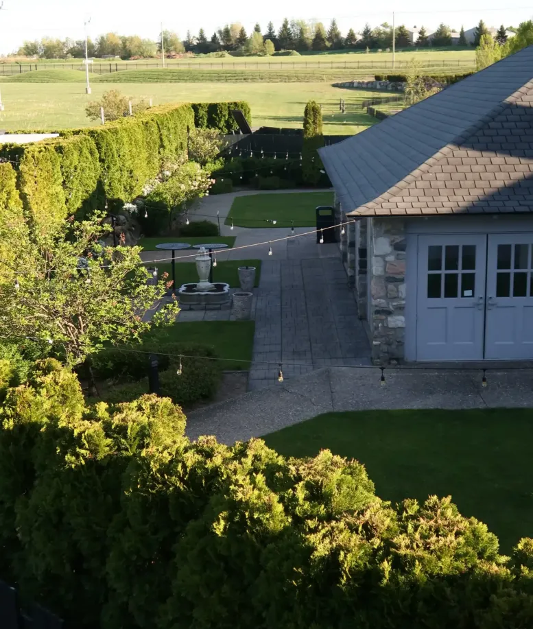 A yard with pavement, hedges, and string lights  next to a building at Castle Farms.
