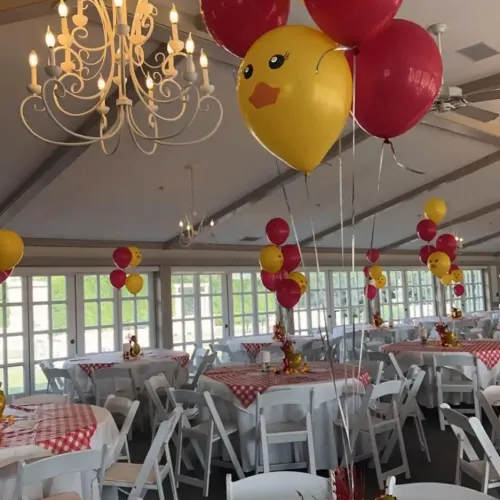 A group of balloons floating above a red checkered tablecloth on a table in an event space at Castle Farms.