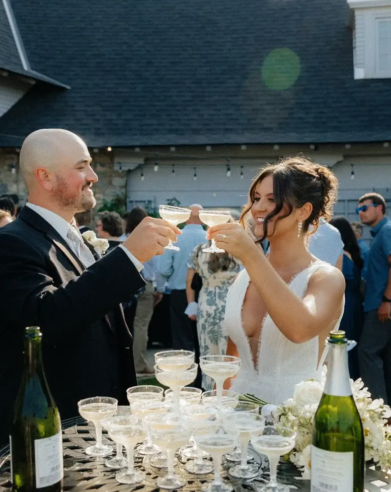 A bride and groom raising glasses of champagne in a courtyard at Castle Farms. 