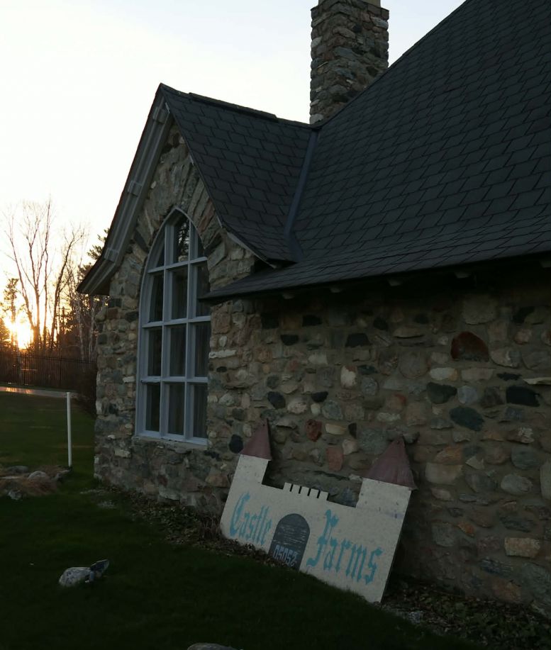 A sign labeled "Castle Farms" leaning on a stone building at Castle Farms.