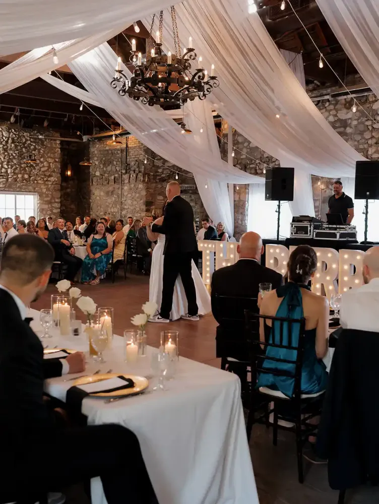 A bride dancing on the dance floor in an event space decorated with white sheets and string lights at a reception at Castle Farms.