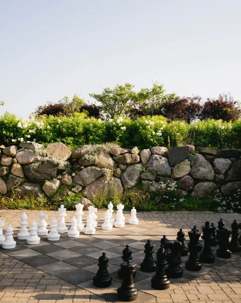 A jumbo chess set beside a stone wall and greenery at Castle Farms.