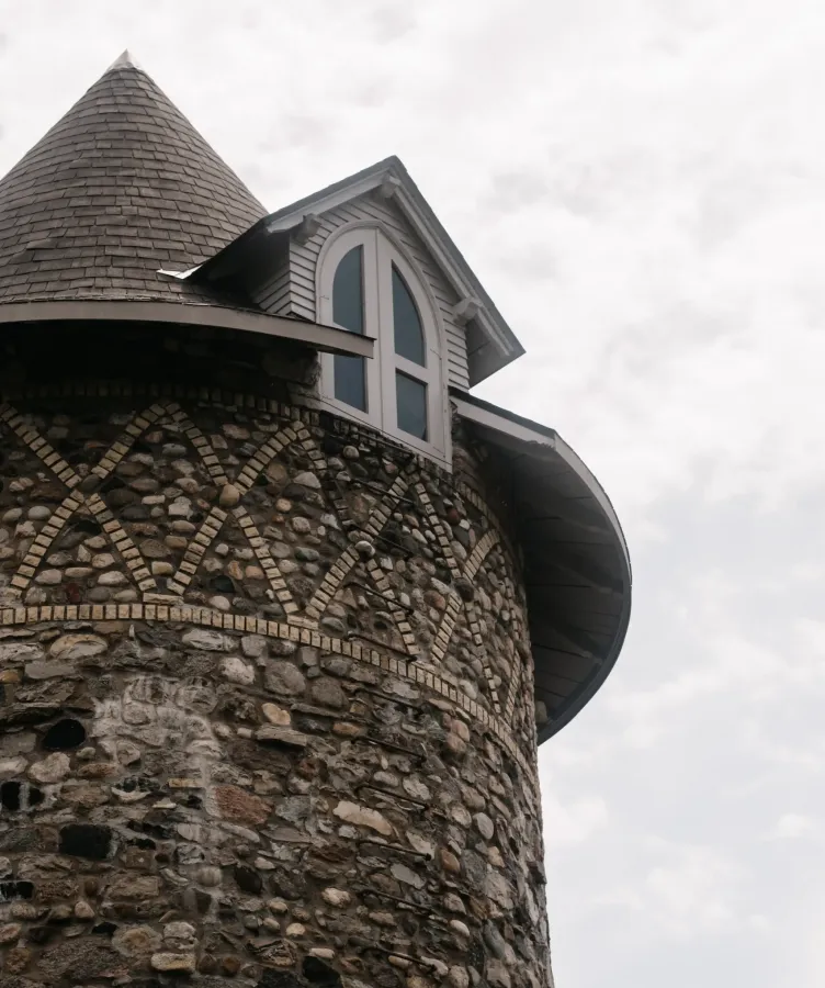 A stone tower with a window on a cloudy day at Castle Farms.