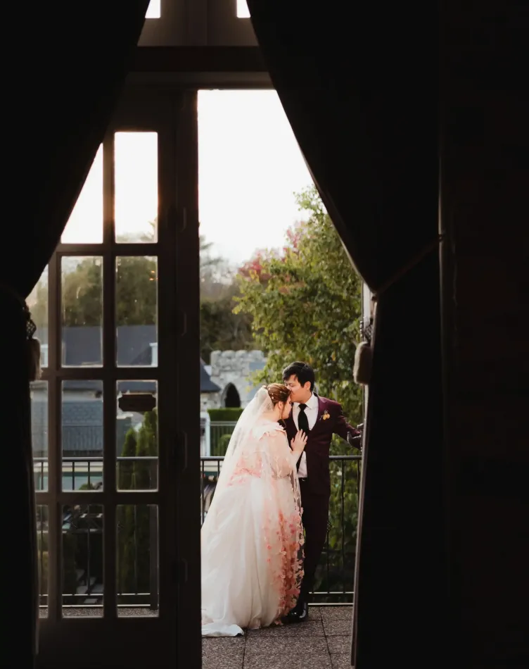 A bride and groom embrace on a balcony at Castle Farms.